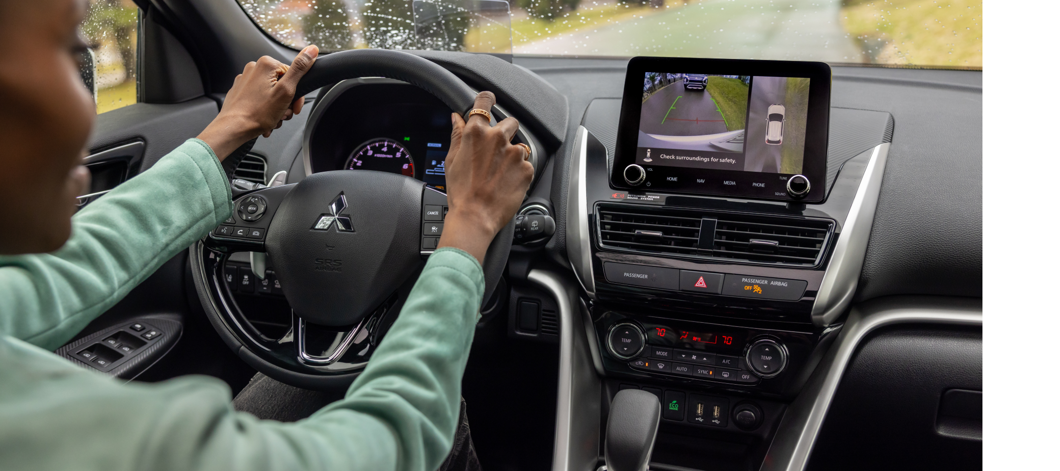 The front interior of a 2025 mitsubishi eclipse cross showcasing the infotainment setup and digital display cluster with a person in the drivers seat