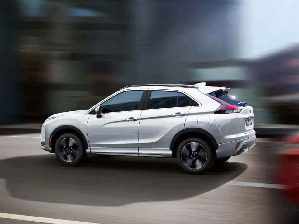 a silver 2025 mitsubishi eclipse cross with a blurbed background driving on a paved road