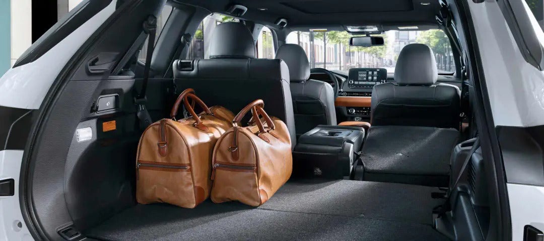 Spacious cargo area of the 2025 Mitsubishi Outlander PHEV with luggage bags, demonstrating ample storage capacity.