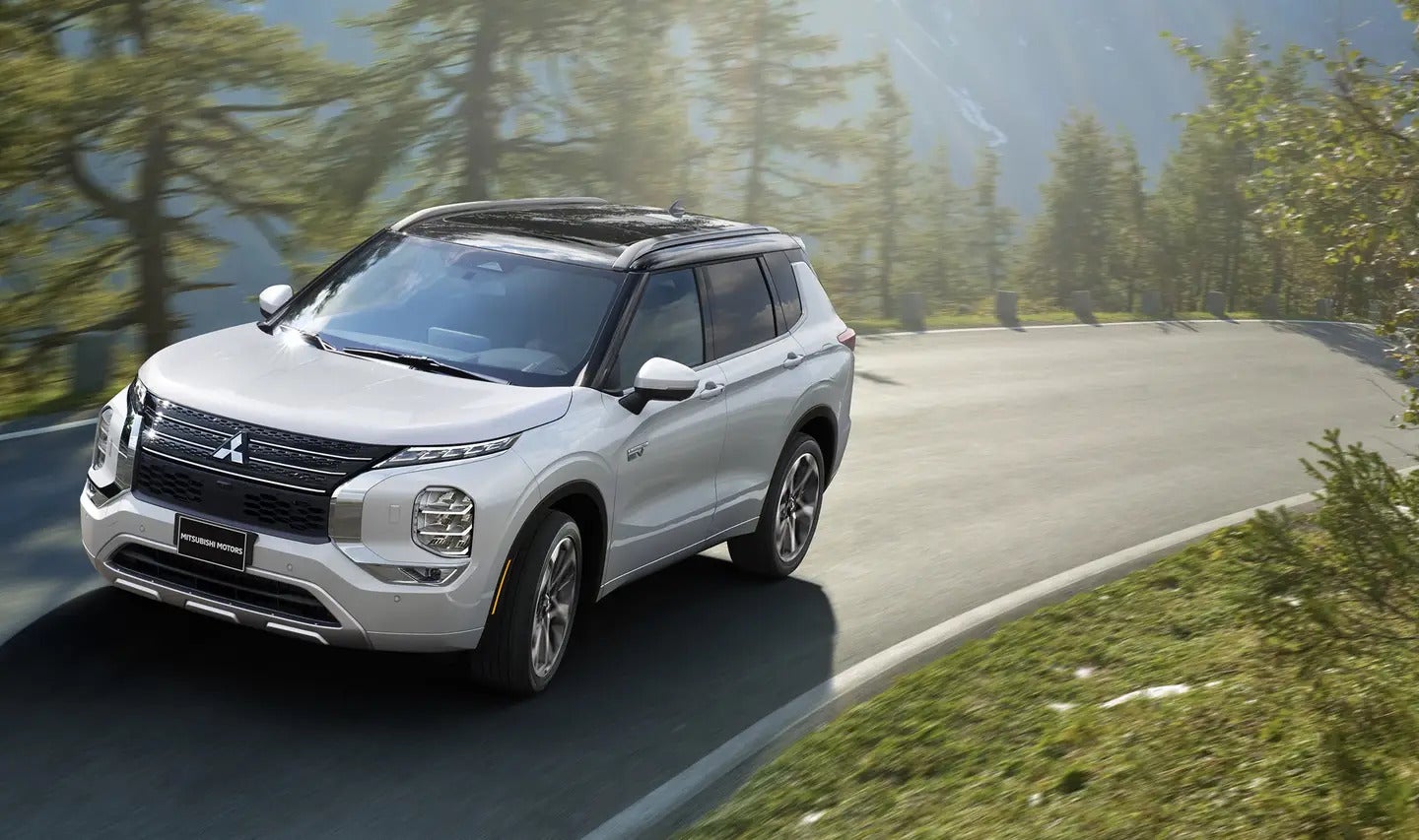2025 Mitsubishi Outlander PHEV driving on a sandy desert road, showcasing its off-road capabilities.