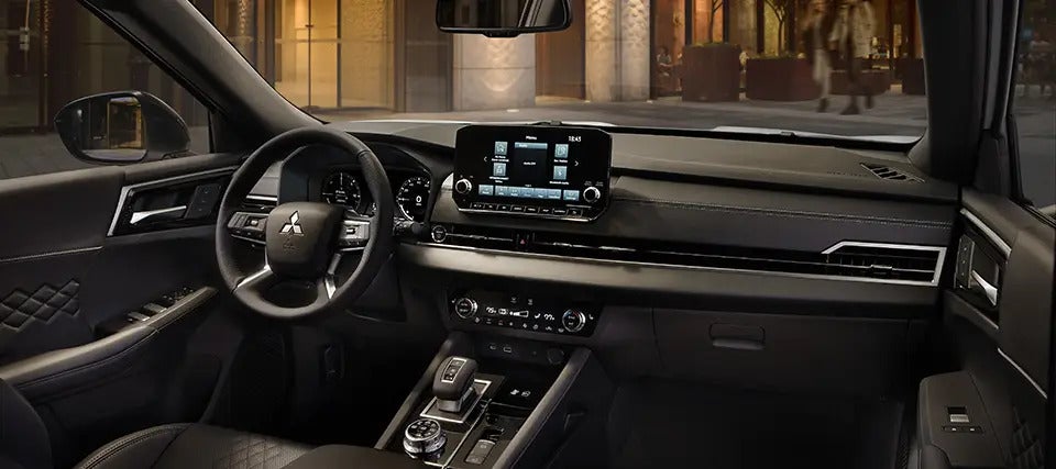 Front interior view of the 2025 Mitsubishi Outlander PHEV, highlighting the dashboard and driver’s seat.