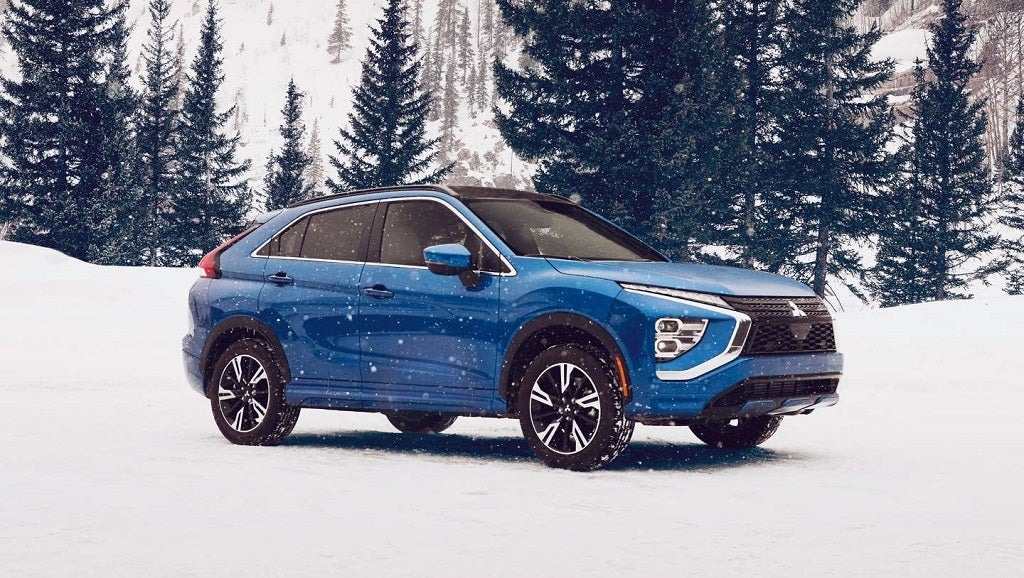 A blue eclipse cross sitting parked in the snow.