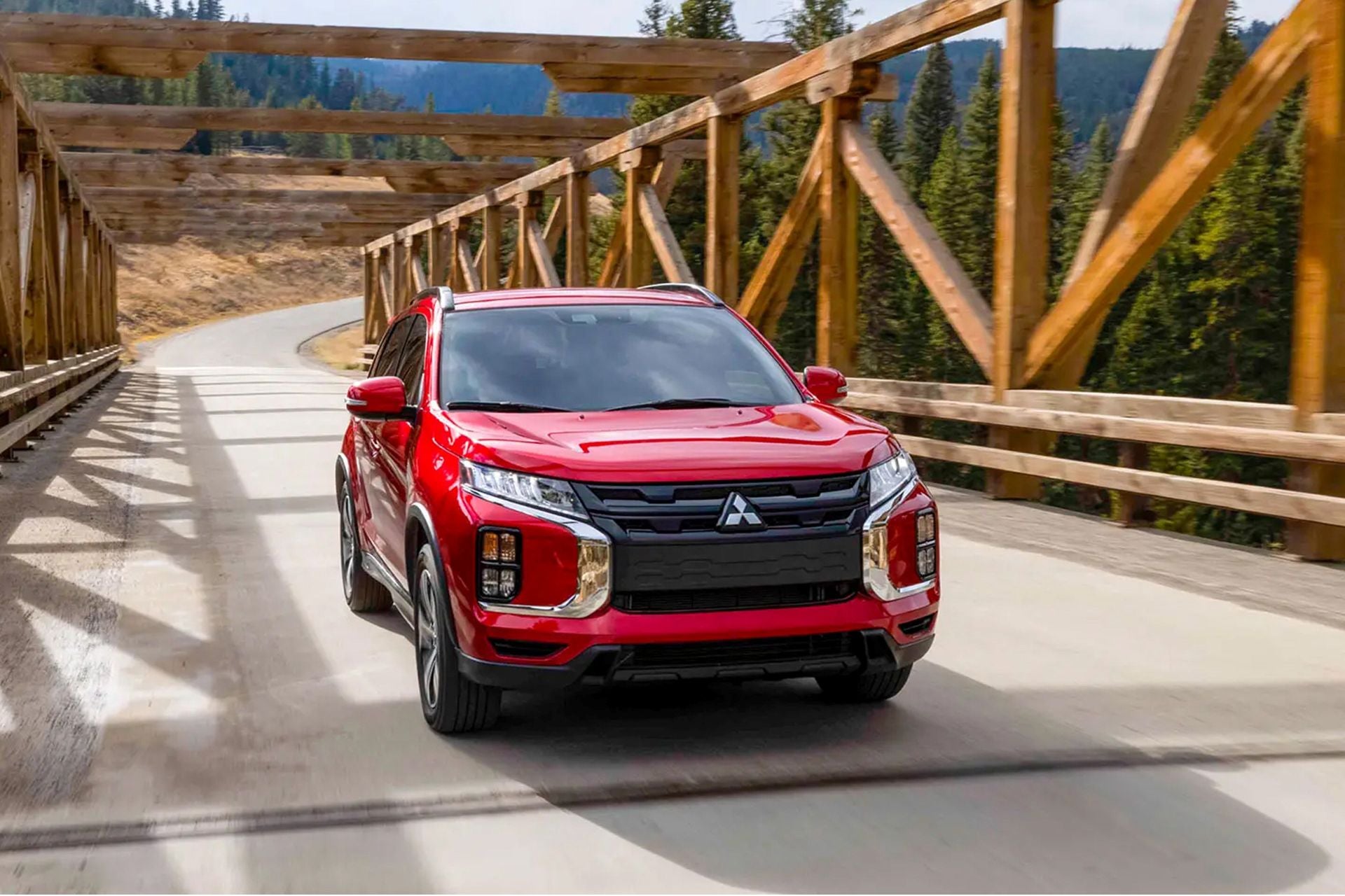 A red outlander sport driving over a bridge.
