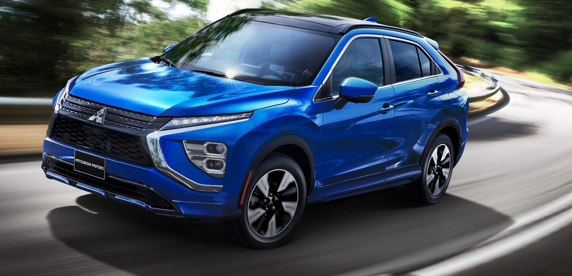 a blue mitsubishi eclipse cross driving on a winding paved road in the mountains