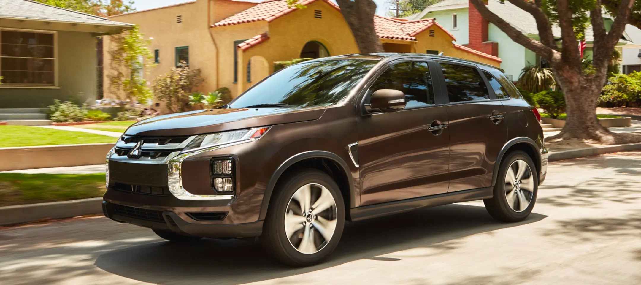 a brown outlander sport parked on next to house