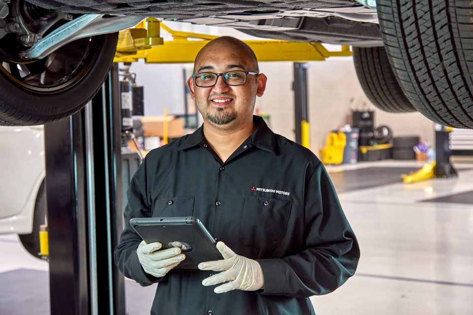 a mitsubishi service technician with a clipboard in front of a vehicle