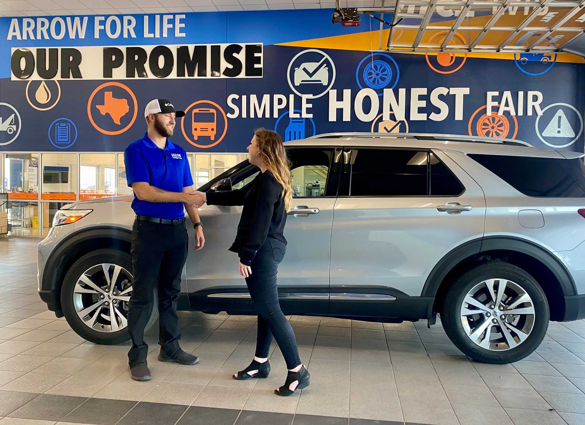 A man and woman skaing hands inside a dealership.